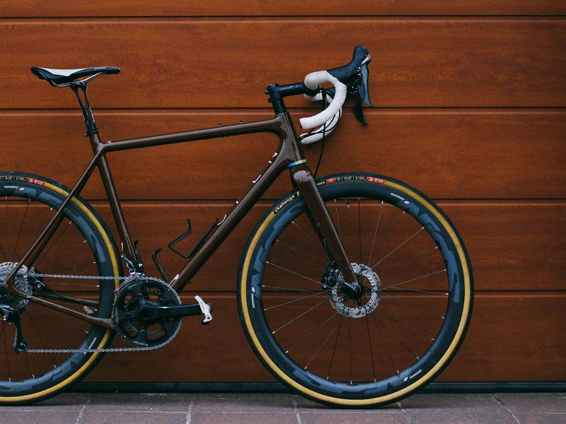 Braunes Gravelbike vor einem Holztor